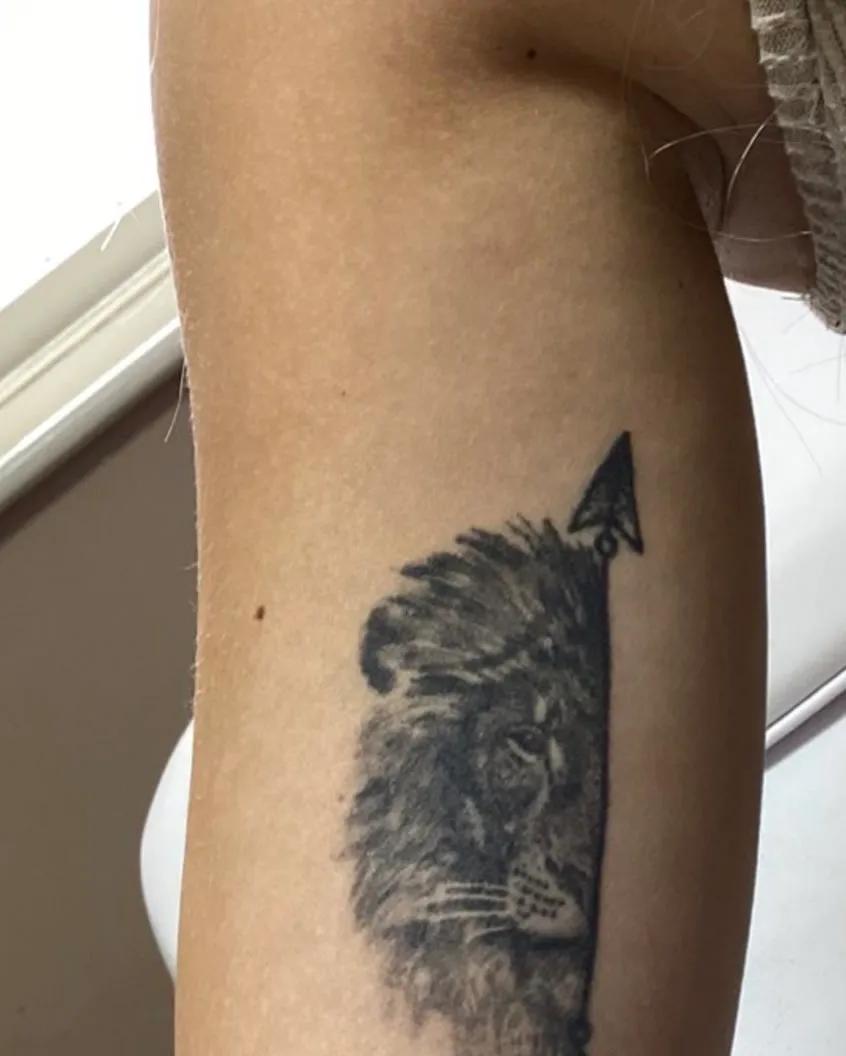 A lion and arrow tattooed on an upper arm, before laser removal