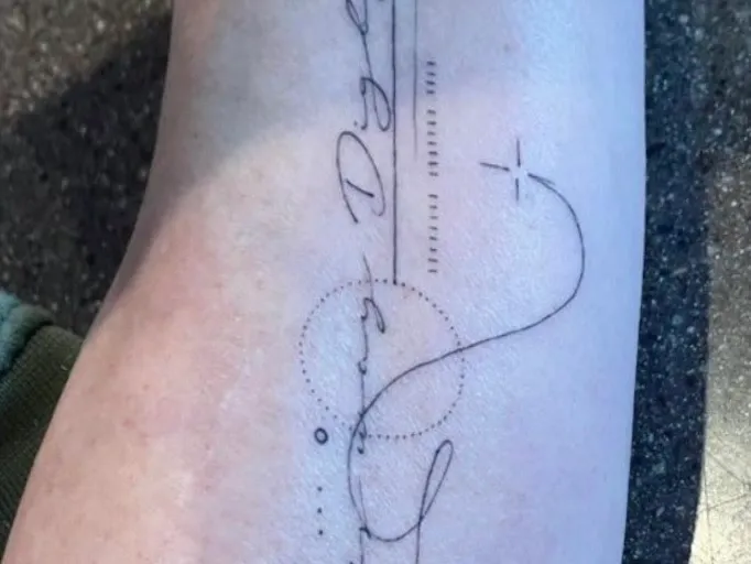 A script tattoo running down a forearm, before laser removal