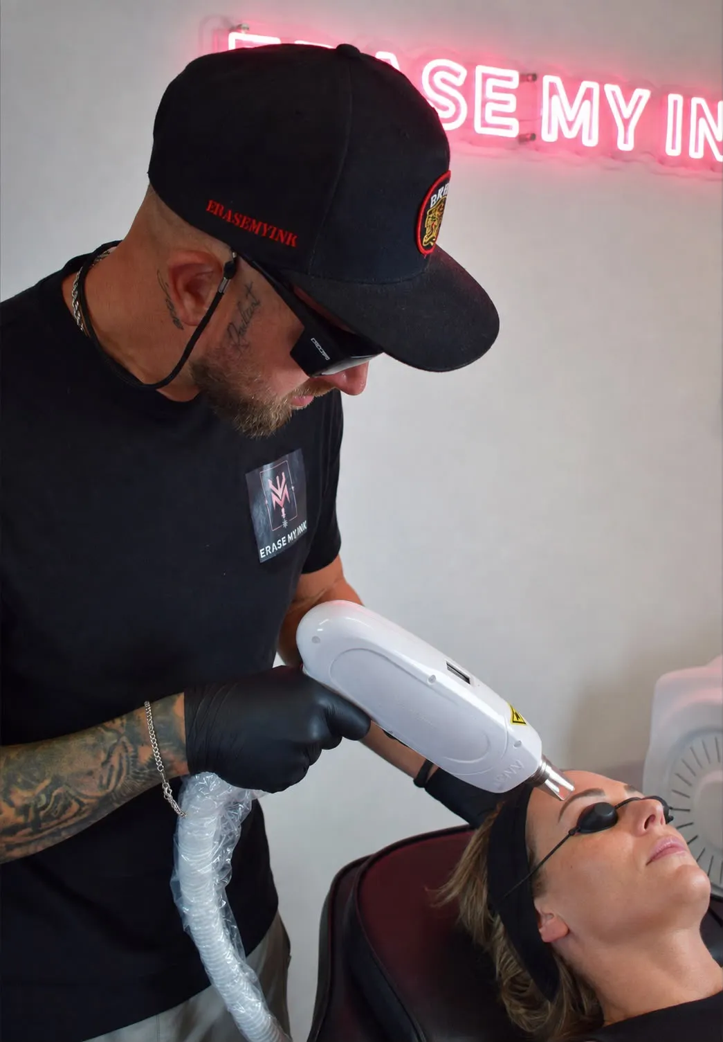 Aaron treating a client’s eyebrow SPMU with the laser, the client wearing protective eye shields